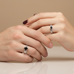 Load image into Gallery viewer, Two hands wearing silver rings with black gemstones on a beige background